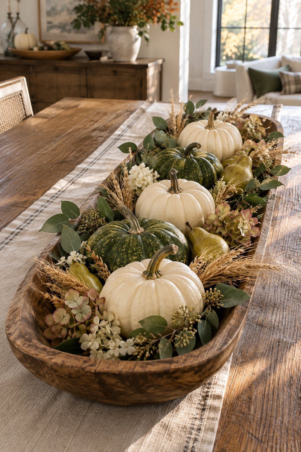 Long wooden dough bowl filled with whole pumpkins, pears, and dried wheat