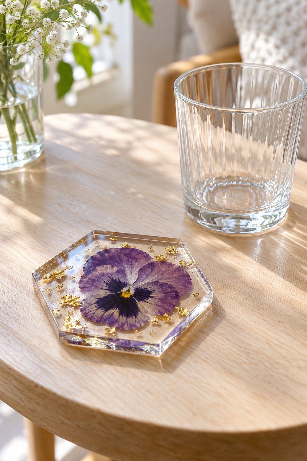Clear resin coaster preserving a purple pressed pansy with scattered gold flakes