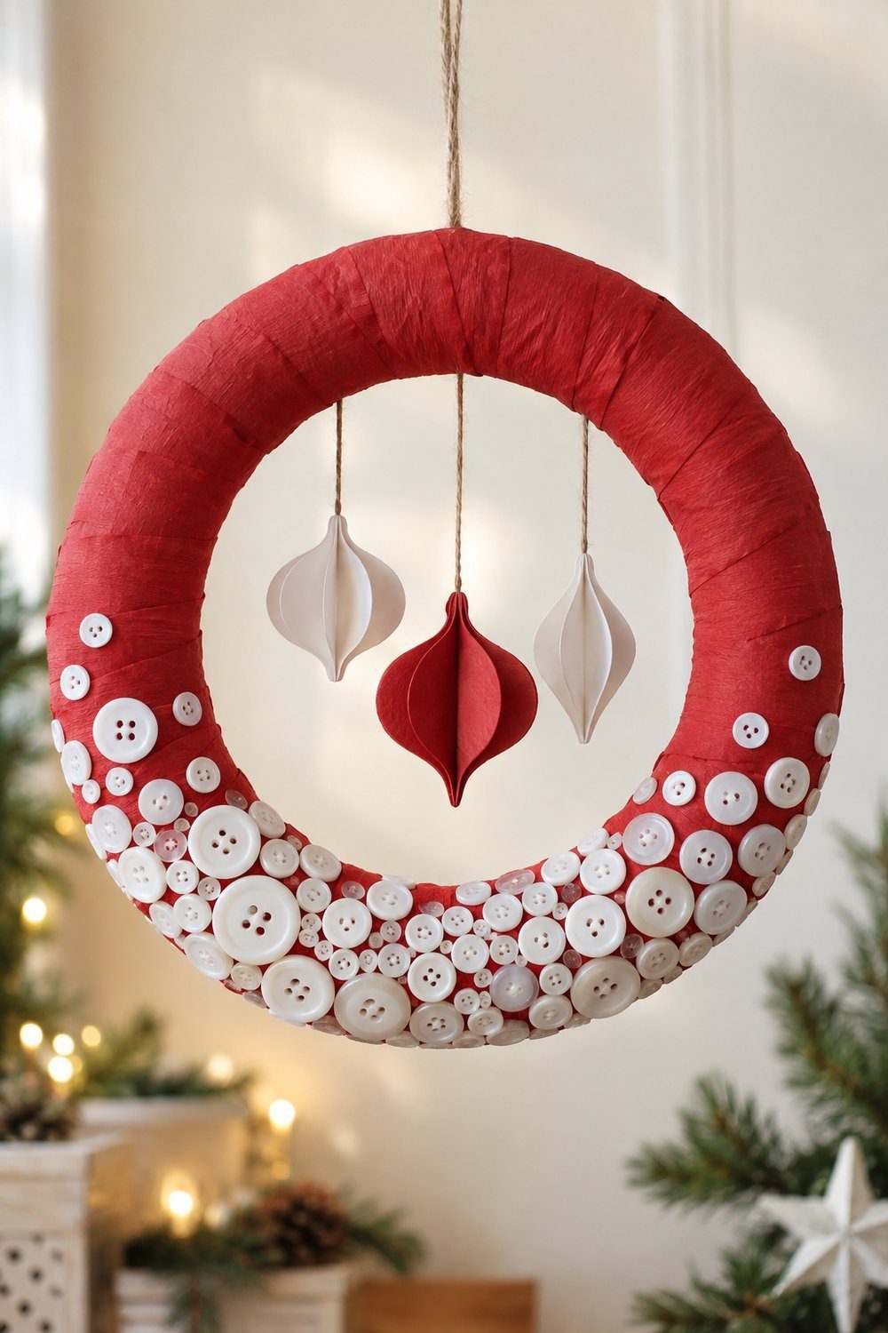 A red paper covered ring wreath has white buttons clustered like snow toward its lower